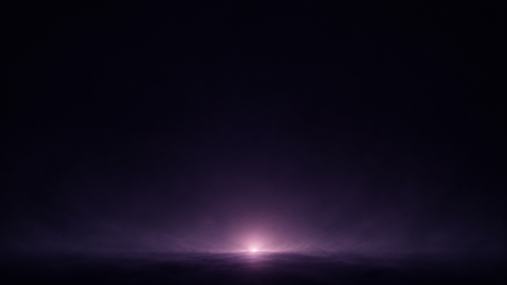 A single soft glow settling low in vast velvet dark
